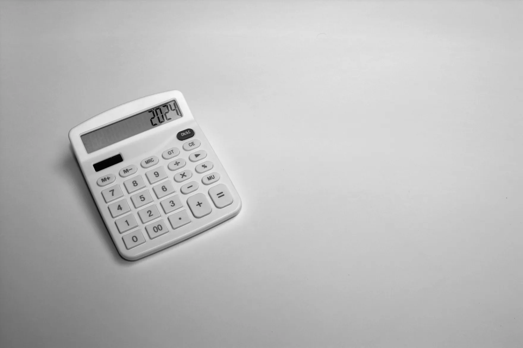 A white desk calculator on a light grey surface