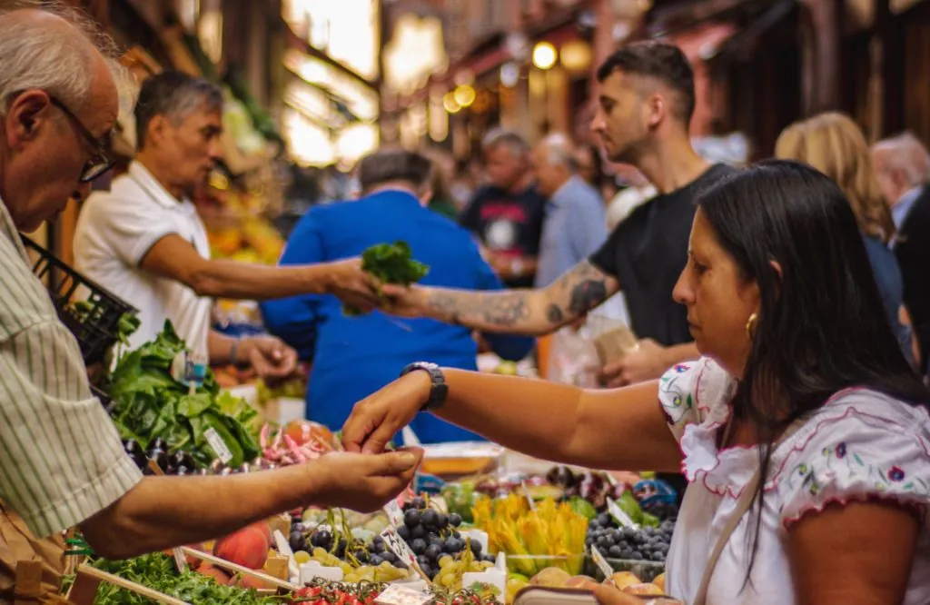 Vendors and customers at a busy fruit and vegetable market stall